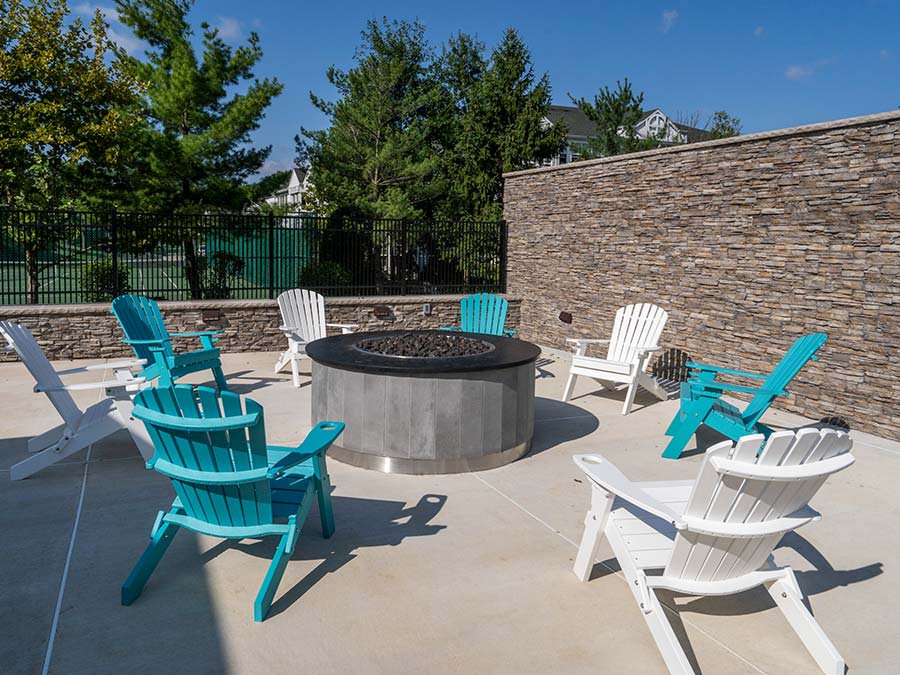 fire pit surrounded by adirondack chairs in the outdoor space at Edge of Yardley apartments